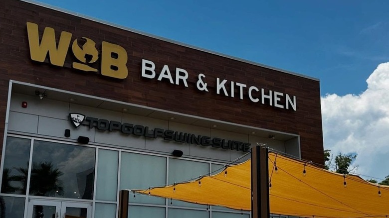 World of Beer restaurant exterior with orange patio sun shades on bright day with big clouds