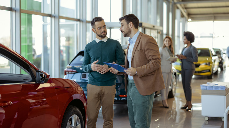 People buying cars at a car dealership.
