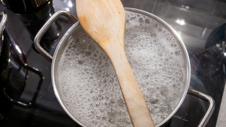 A wooden spoon placed across the top of a pot of boiling water to help prevent it from boiling over.