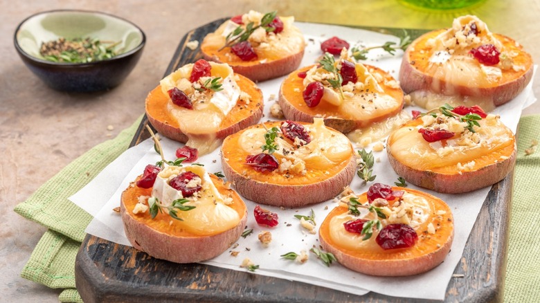 Baked sweet potato rounds topped with cheese, cranberries, and walnuts