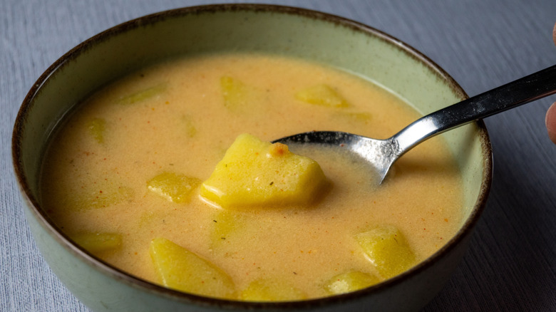 A closeup of a bowl of potato soup with a spoon in it