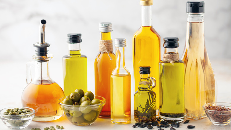Rows of different oils in various bottles sitting in front of a white background.