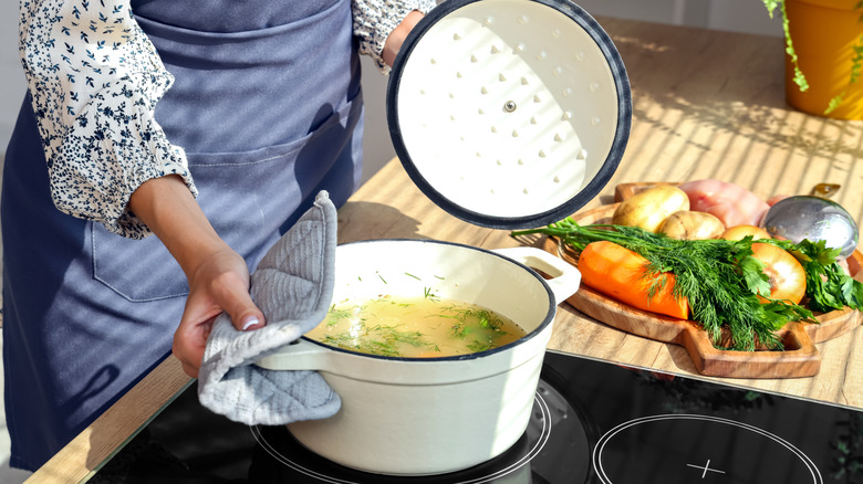 A woman makes chicken soup on the stovetop