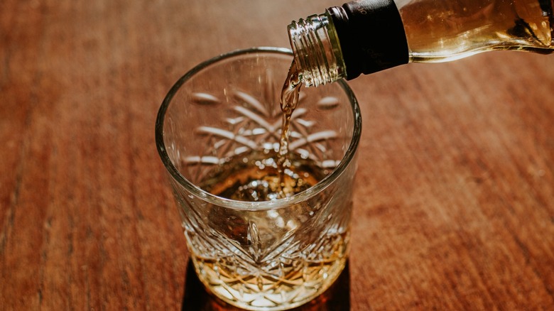 Whiskey is poured into a rocks glass.