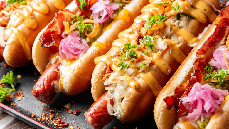 Close up of hot dogs with different toppings on a black tray