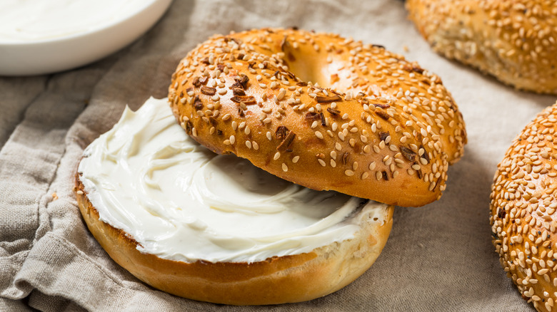 An everything bagel, sliced and spread with cream cheese