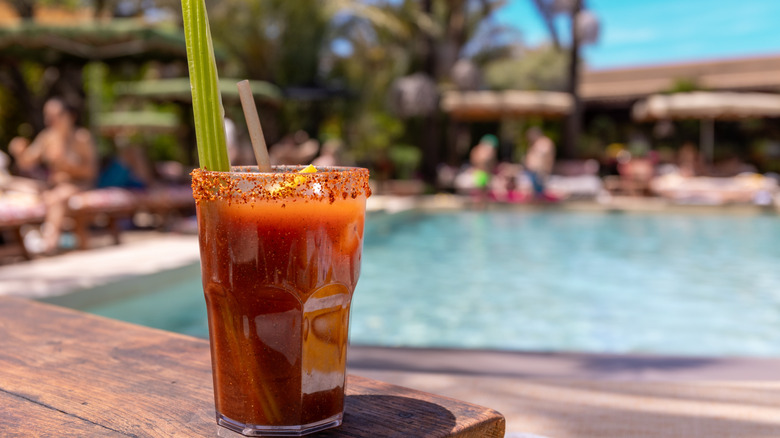 A Bloody Mary with garnishes on a poolside table
