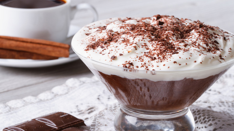 chocolate pudding with whipped cream next to coffee