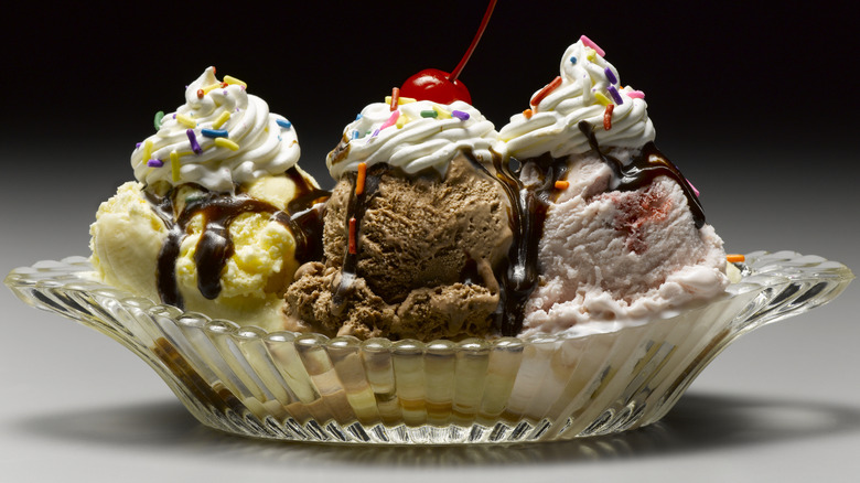 A three scoop ice cream sundae in a glass bowl