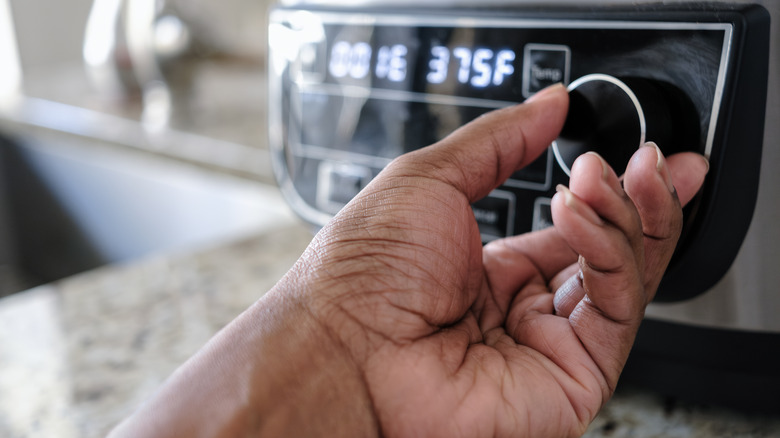 Close-up of a woman's hand changing the temperature on the air fryer
