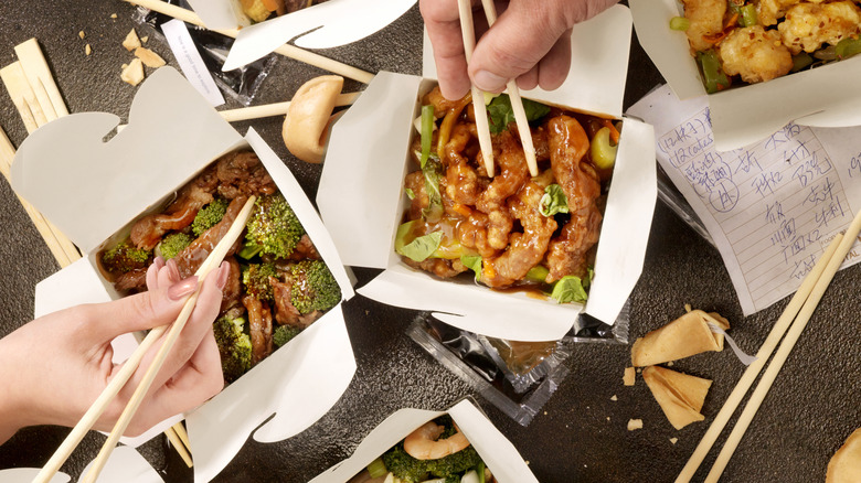 People using chopsticks to eat Chinese takeout
