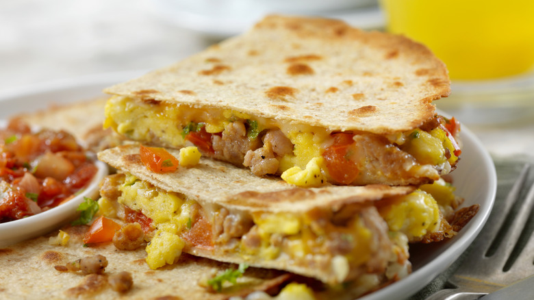 Breakfast quesadilla with eggs, sausage, cheese, and tomatoes on a plate