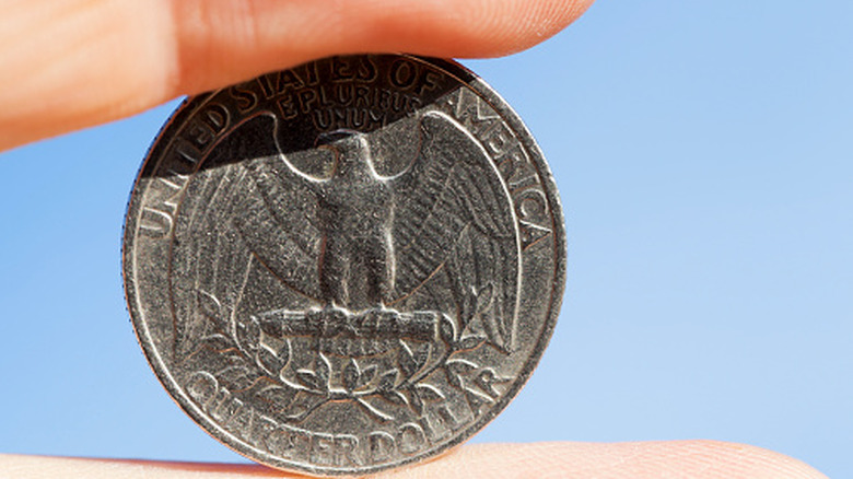 Two fingers holding a quarter between them.