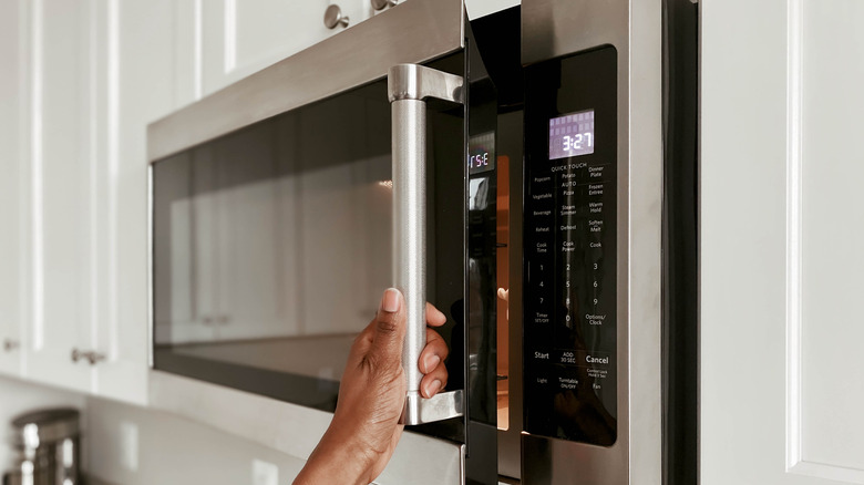 A person opening a microwave oven