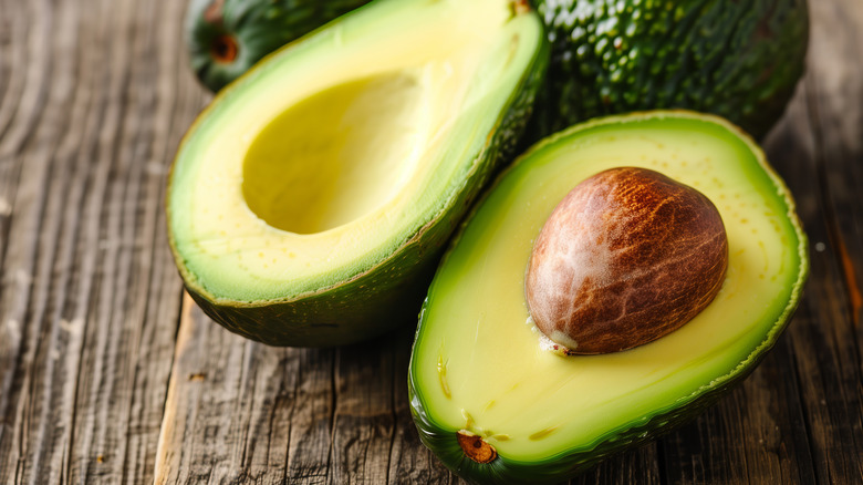 Sliced avocado with pit on wooden board