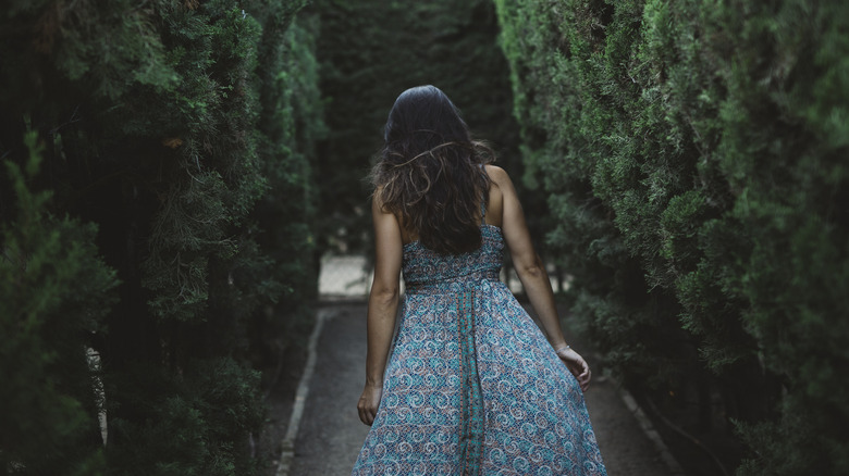 A young woman peers into an enchanted forest