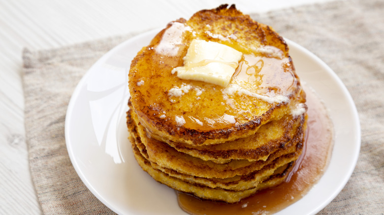 Johnnycakes on a white plate with butter and syrup