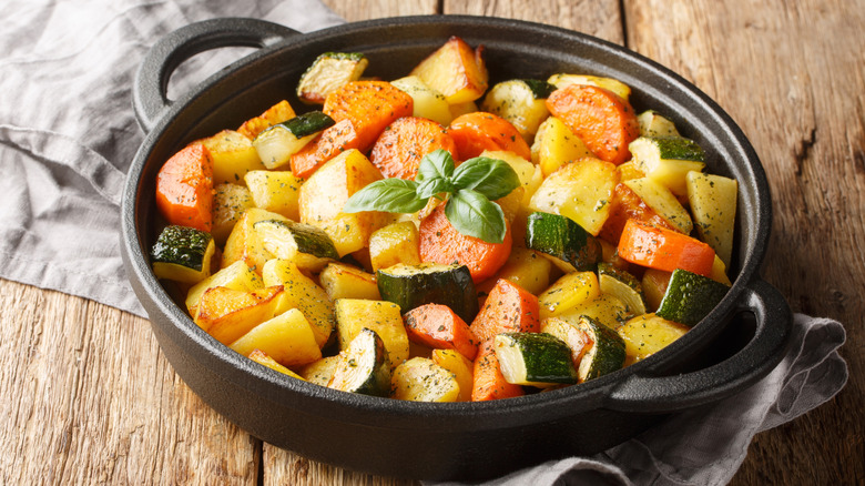 Cast iron skillet filled with roasted potatoes, carrots, and squash.