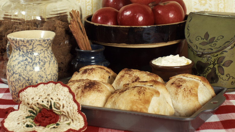 Baked Apple Dumplings on Counter with Fresh Apples and Vintage Cookware