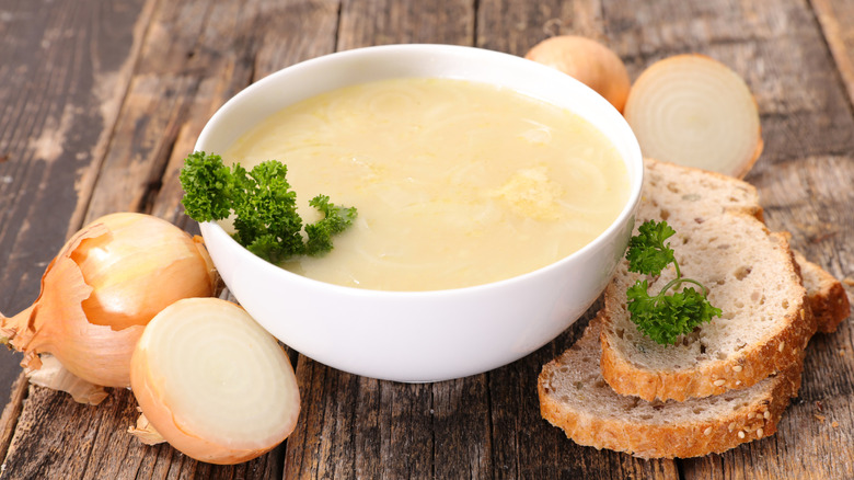 Bowl of Onion Soup with Garnish and side of bread and whole onions