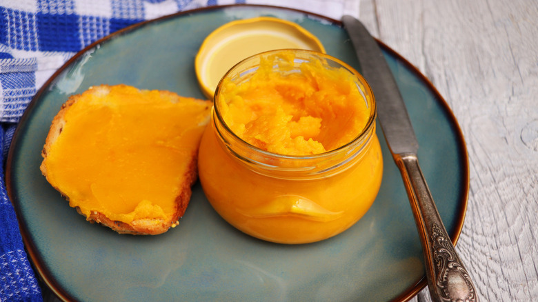 Glass Jar of Pumpkin Butter and Slice of Bread Spread with Pumpkin Butter on plate