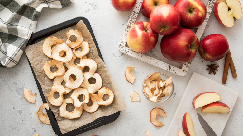 Apple rings on baking sheet next to whole and sliced apples
