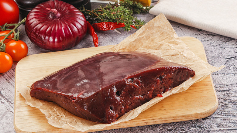 Raw beef liver on a wooden cutting board