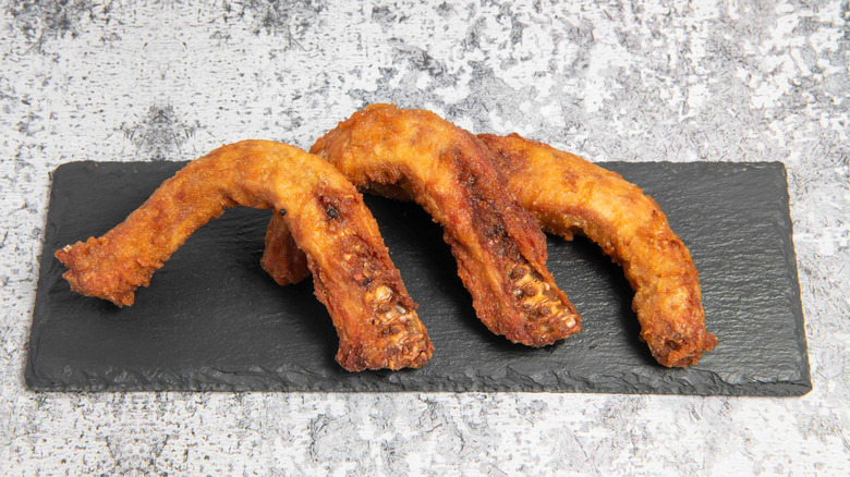 Three fried chicken necks on a black board