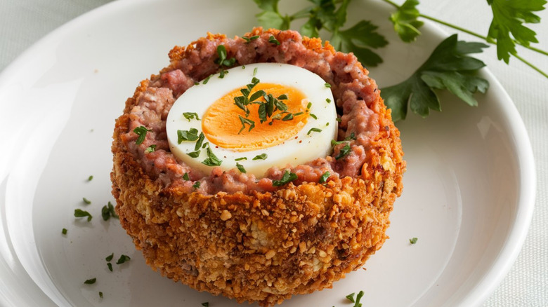 A Scotch egg cut open on a white plate