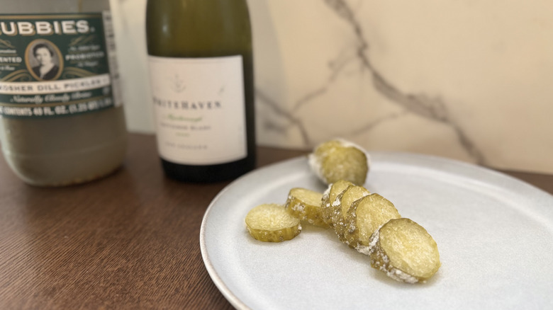 Sliced pickles with wine and pickle jar in the background