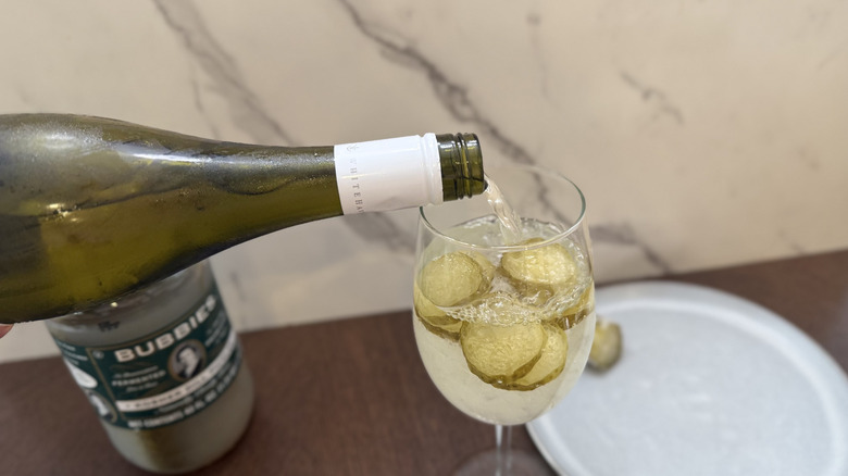Pouring wine into a glass with ice and frozen pickle chips
