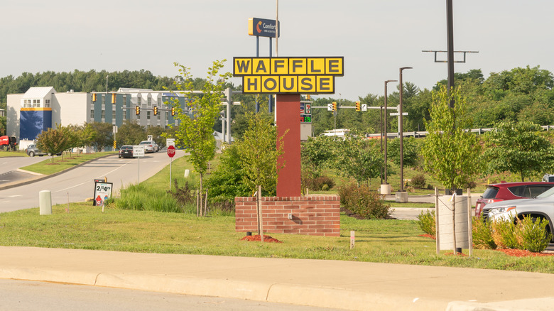 A Waffle House sign on the side of a highway.