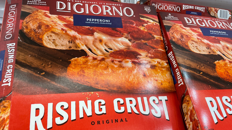 Pizza box of DiGiorno rising crust pepperoni pizza on freezer shelf next to other boxes