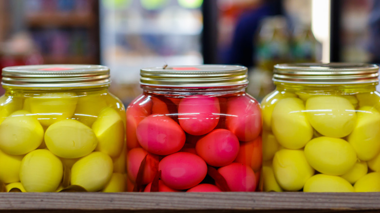 Jars of yellow and pink pickled eggs