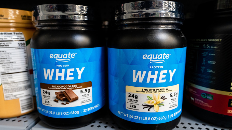 Containers of Equate protein whey, on a shelf at Walmart