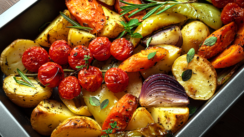 A pan full of roasted vegetables with herbs and seasonings on top