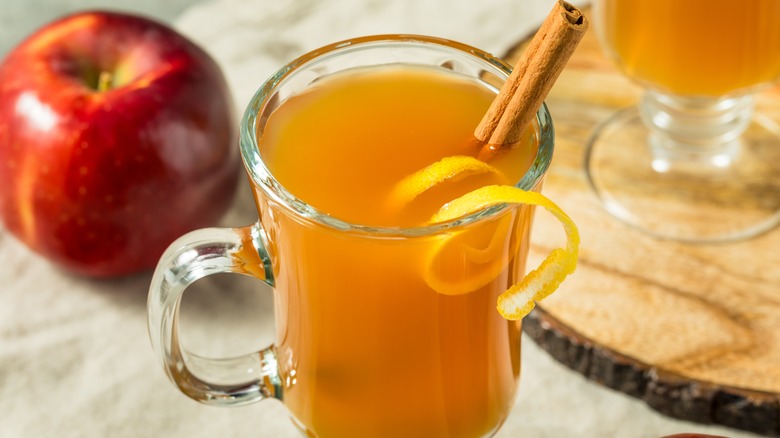 Hot toddy with cinnamon stick and orange garnish. Apple off to the side