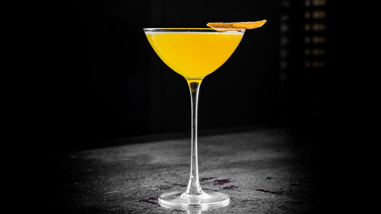 Bright yellow cocktail in coupe glass on black background