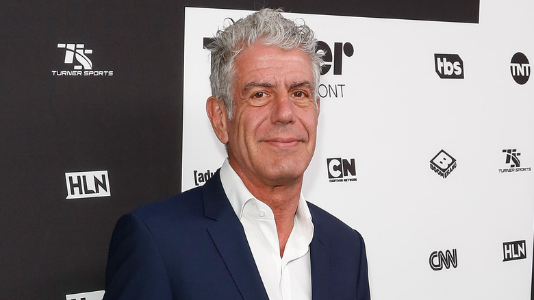 Anthony Bourdain smirking in a navy blue suit at a Turner Broadcasting event