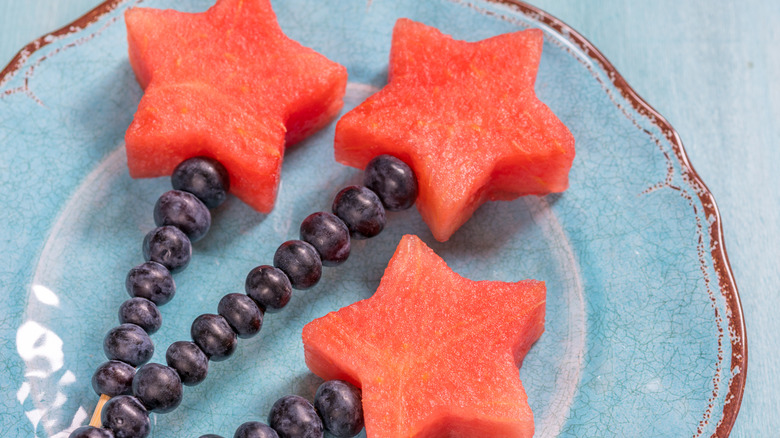 Watermelon sparklers made up of star-shaped watermelons and blueberries on skewers