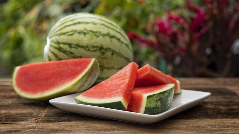 Whole and sliced watermelon outside on wooden table