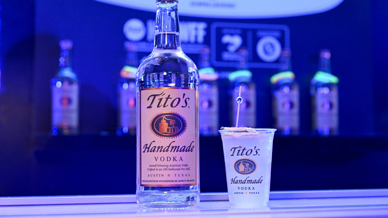 Bottle of Tito's vodka next to a full plastic cup with a Tito's logo