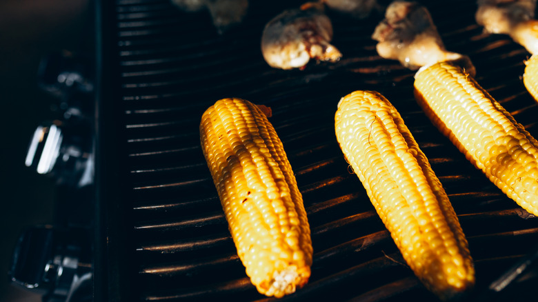 Corn cobs cooking on grill grates