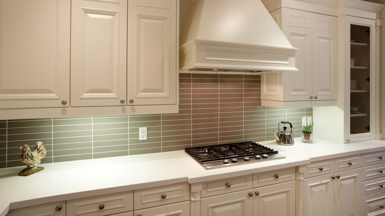 White kitchen cabinets and a stove with a white hood with lighting underneath the top cabinets