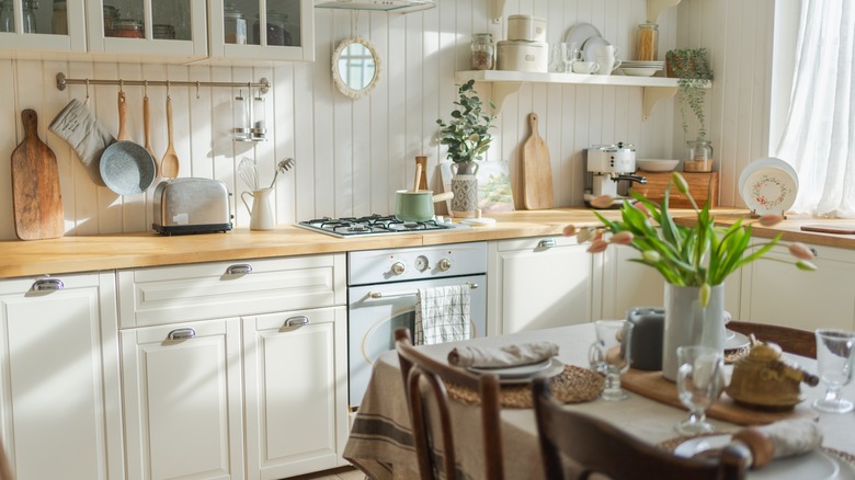 Kitchen with white walls and cabinets with butcher block tops and a set table in the foreground