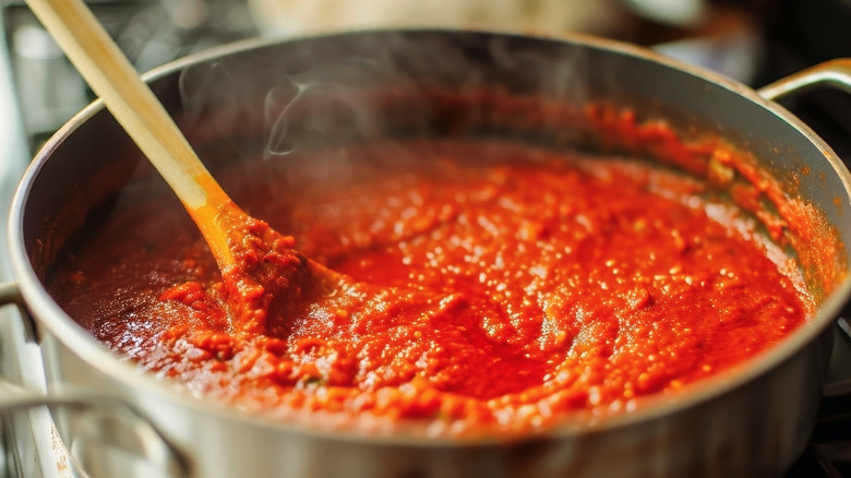 A close up of tomato sauce steaming in a pot on the stove