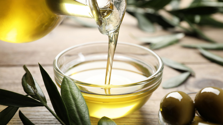 Pouring extra virgin olive oil into a glass bowl