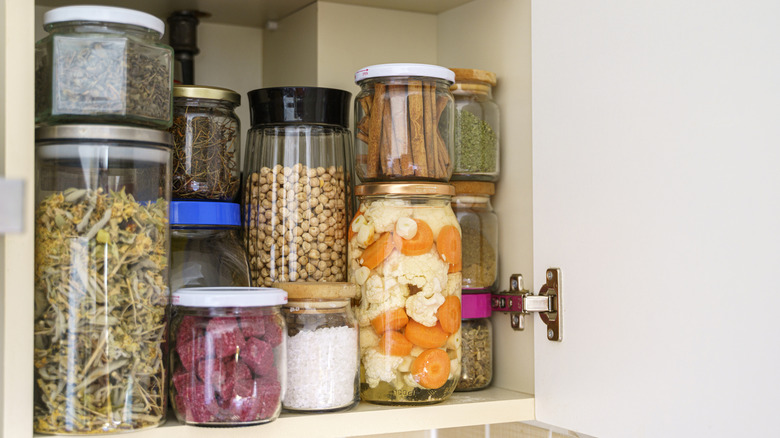 Pantry shelf with herbs, spices, pickles, and dried goods in jars