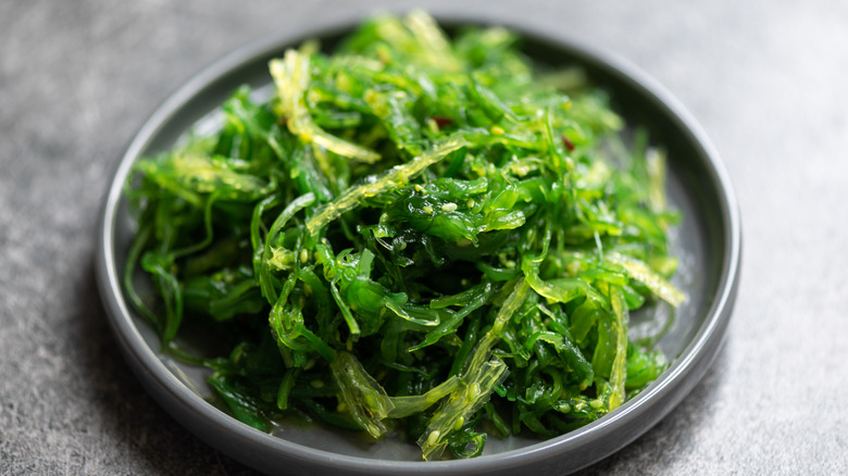 A bright green seaweed salad in a small dish
