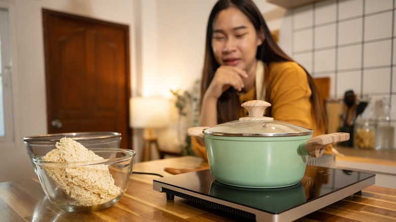 asian woman in an apron stands in a kitchen, preparing a quick and easy meal